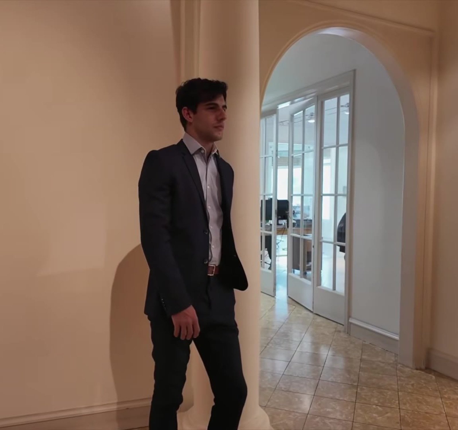 Artur Margalef con traje caminando por un pasillo luminoso